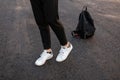 Close-up of male legs. Young fashionable guy in vintage black pants in leather stylish white sneakers posing standing Royalty Free Stock Photo