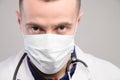 close-up of a male medic face with a serious aggressive look in a medical mask. He looks from under his brows into the