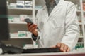 Close up of male pharmacist using the computer and phone while working at the pharmacy Royalty Free Stock Photo