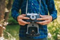 Close up of male photographer hands holding retro camera on green garden background.