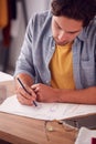 Close Up Of Male Student Or Business Owner Working In Fashion Sketching Designs In Studio