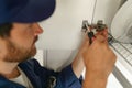 Close up of professional repairman is using a screwdriver to adjust door of cabinet in kitchen Royalty Free Stock Photo