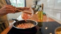 Close up of man adding shrimp to sauteed garlic and onion in the frying pan. Cook preparing dish with seafood