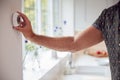 Close Up Of Man Adjusting Wall Mounted Digital Central Heating Thermostat Control At Home