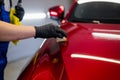 Close-up man applying ceramic coating on the red car at detailing service.