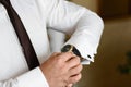 Close-up man arranging his buttonholes on a background of a white shirt, Groom wearing clock on wedding day. sleeve shirt and watc Royalty Free Stock Photo