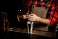 Close-up man bartender pours cocktail from bowl into metal martini glass. Royalty Free Stock Photo