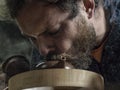 Close-up A man with a beard breathes smoke into a traditional teapot made of yixing clay. brown pottery teapot