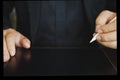 Close up a man in a black shirt holding an electronic pen to write on a tablet on a wooden table Royalty Free Stock Photo