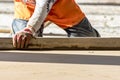 Close up of man builder placing screed rail on the floor covered with sand-cement mix at construction site. Male worker leveling