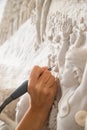 Close up of man ceramist hands holding a tool and working on sculpture details in workshop. Royalty Free Stock Photo