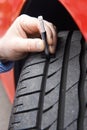 Close-Up Of Man Checking Tread On Car Tyre With Gauge