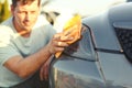Close up of man cleaning car with microfiber cloth