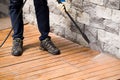 Close up of a man cleaning terrace with a power washer - high water pressure cleaner on wooden terrace surface Royalty Free Stock Photo