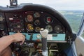 Close up of a man in a cockpit piloting small four seat airplane, pushing buttons on control panel with hills and meadows in Royalty Free Stock Photo