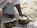 Close up of man cutting a coconut with a big Indian knife. Sale of coconuts. Indian beach market