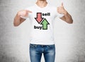 Close up of the man in denims and a white t-shirt pointing out to the chest with drawn arrows: buy and sell. The concept of the ca Royalty Free Stock Photo