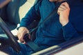 Close up man driver fastening seat belt. Guy seated behind the steering wheel testing his new car safety Royalty Free Stock Photo