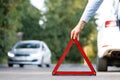 Man driver putting red warning triangle/emergency stop sign behind his broken car Royalty Free Stock Photo