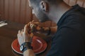 Close up of man eating burger and french fries at cafe. Back view. Royalty Free Stock Photo
