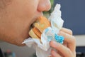 Close up of man eating hamburger with crumpled paper. Royalty Free Stock Photo