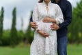 Close up man embraces his pregnant wife and stroking her belly in park, married couple is expecting a baby Royalty Free Stock Photo