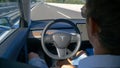 CLOSE UP: Man in a futuristic self-driving car speeds down a empty motorway.