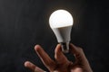 Close-up of man hand holding energy saving LED lamp. Saving energy and energy crisis concept. Lightbulb on the black background Royalty Free Stock Photo