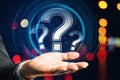 Close up of man hand holding glowing round question mark hologram on blurry bokeh background. FAQ and customer service concept. Royalty Free Stock Photo