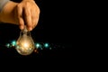 Close-up of man hand holding light bulb on black background. Ideas Royalty Free Stock Photo