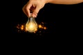 Close-up of man hand holding light bulb on black background. Ideas, innovations Royalty Free Stock Photo