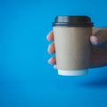 Close up of Man Hand Holding a Recycle Brown Paper Coffee Cup on a Blue Background, Mockup Template for Logo Design, Branding, Royalty Free Stock Photo