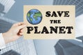 Close up of man hand holding save the planet sketch on city background. Earth day concept Royalty Free Stock Photo