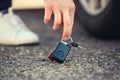 Close up of man hand lifting car keys fallen on the ground. Guy found vehicle keys someone lost on the asphalt road in the parking