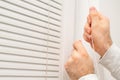 Close up man hand opening horizontal window blinds with copy space Royalty Free Stock Photo