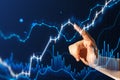 Close up of man hand pointing at glowing and growing business chart on blurry blue background. Financial growth, trade and stock Royalty Free Stock Photo