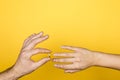 Close up of man hand putting an engagement ring on a woman hand on yellow background Royalty Free Stock Photo