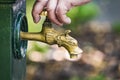 Close up of a man hand turning on or off the faucet of vintage brass tap with drinking water on the city street or park. Flowing