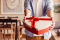 Close up of man hands giving a present gift towards camera - holidays theme - in warm sunlight