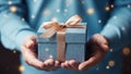 close up of man hands holding blue gift box with gold ribbon bow Royalty Free Stock Photo