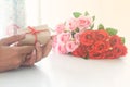 Close up man hands holding gift box and roses on white table Royalty Free Stock Photo