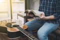 close up of a man hands holding and read book with guitar on wooden table Royalty Free Stock Photo