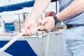 Close up of man hands holding rope. Close-up of rope in yachtsman hands. White Rope and black watch.