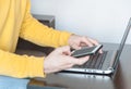 Close up man hands holding smart phone in front of the laptop. Businessman or student working or studying from home concept Royalty Free Stock Photo