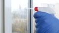 Close Up Man Hands with Protection Gloves Cleaning a Window Using Sprayed Liquid Disinfecting Against Viruses Contamination