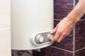 Close-up of man hands setting the temperature of water in Electric Boiler.