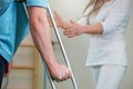 Close-up of man holding crutch during rehabilitation with woman physiotherapist.