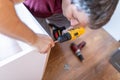 Close up of man holding electrical battery screwdriver while installing wooden kitchen shelves Royalty Free Stock Photo