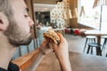 Close-up. A man is holding a hamburger in his hand at dinner in a cafe