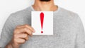 Close-up of a man holding a piece of paper with a red exclamation mark on it Royalty Free Stock Photo